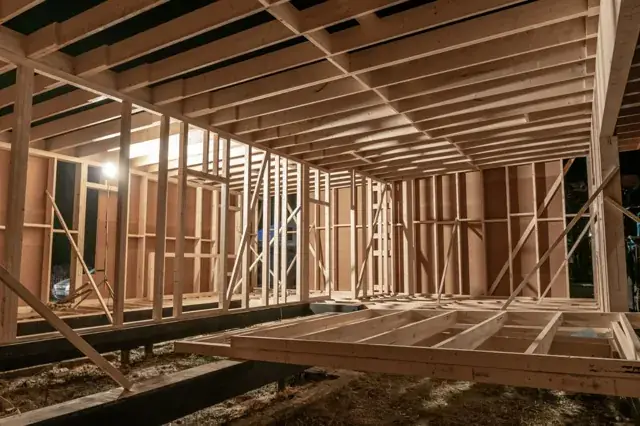 Moduļu mājas koka karkass un pārsegums naktī ražotnes gaismā